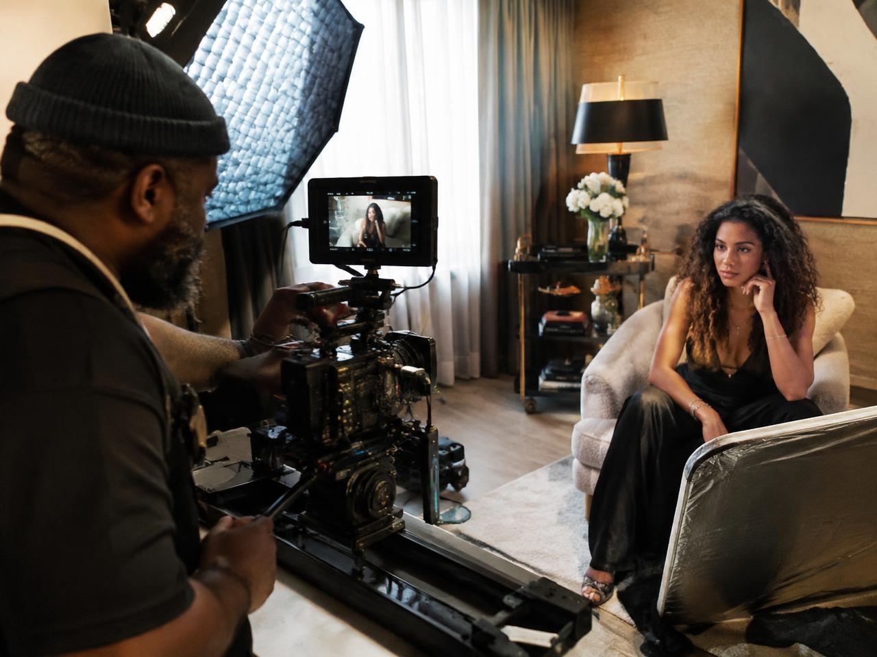 African cinematographer filming a premium brand shoot with a model on a luxury set